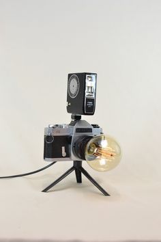 an old fashioned camera on a tripod with a light bulb