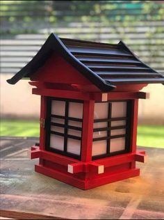 a small red and black building sitting on top of a wooden table next to a window