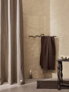 a bath room with a shower curtain and a towel hanging on the wall next to a table