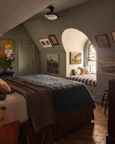 a bedroom with two beds and pictures on the wall above them in an arched window