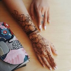 a woman's hands with henna tattoos on her left arm and right hand