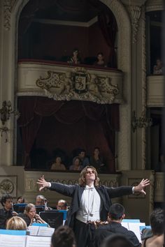 conductor in front of orchestra with arms outstretched