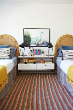 two twin beds in a bedroom with blue and white bedding, striped rug on the floor