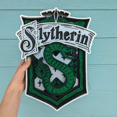 someone is holding up a sticker that says slytherin on it and a green dragon in the middle