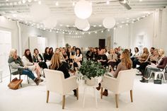 a group of women sitting in chairs talking to each other