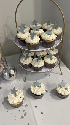 cupcakes are arranged on three tiered trays with stars and silver confetti