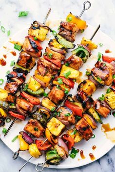 chicken and vegetable kabobs on a white plate with chopsticks next to it