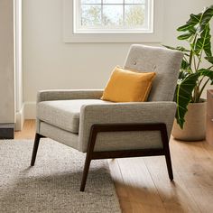 a chair sitting in front of a window next to a potted plant on top of a hard wood floor