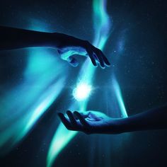 two hands reaching towards each other in front of an aurora bore with green and blue lights