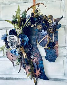 a horse head decorated with blue flowers and greenery is hanging on a white door