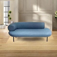 a blue couch sitting on top of a hard wood floor next to a vase filled with flowers