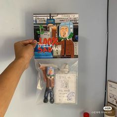 a hand is holding an action figure next to a package with the same character on it