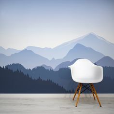 a white chair sitting in front of a wall mural with mountains and trees on it