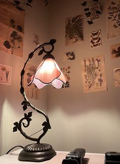 a lamp sitting on top of a table next to a cell phone and pictures hanging on the wall