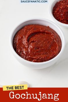 two white bowls filled with red chili paste on top of a white table next to a spoon