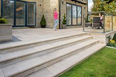 a woman is walking up the steps to her patio with chairs and table in the background