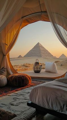 a bed sitting in the middle of a desert next to a tent with mountains in the background