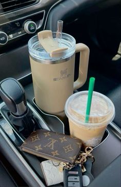 there is a drink and wallet in the cup holder on this car dashboard, along with other items