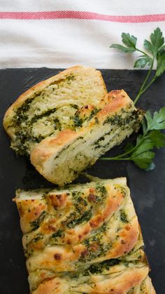 two slices of bread with spinach and cheese on a black plate next to parsley