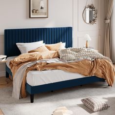 a bed with blue headboard and pillows in a white room next to a window