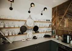 the kitchen counter has many plates and cups on it, as well as hanging lights