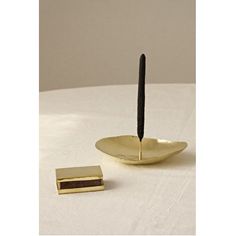 a pen sitting on top of a gold plate next to a small square piece of metal