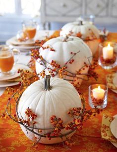 the table is set with white pumpkins and candles