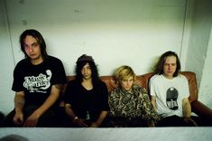 three young men sitting on a couch with one looking at the camera