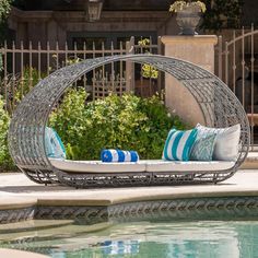 an outdoor daybed with pillows on it next to a swimming pool and fenced in area