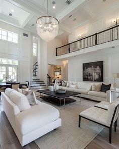 a living room filled with white furniture and a chandelier hanging from the ceiling