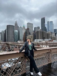 a woman standing on top of a bridge next to tall buildings