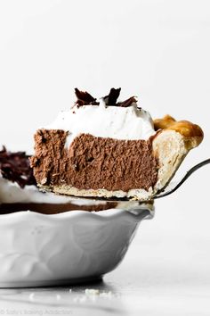 a slice of chocolate pie with whipped cream on top is being held by a fork