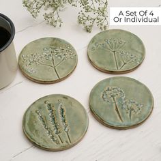 four ceramic coasters with flowers on them next to a coffee cup and flower pot