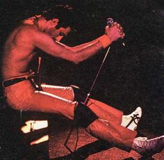 a shirtless man sitting on top of a chair holding a microphone