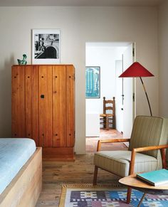 a bedroom with a bed, chair and armoire