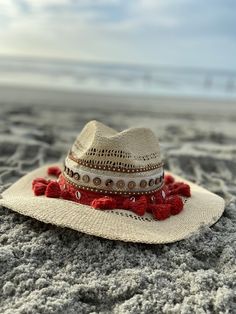 Decorated straw hat, fits size medium to small. Our Dahlia hat is a beautiful and comfortable must have for any occasion. It's decorated with red pom pom, gold and silver seashells, brown button trim and camel suede trim. Each hat is 100% made by hand and made by daily inspirations. No two hats are the same. Summer Beach Hat One Size, Beach Season Hats One Size, One Size Hats For Beach Season Vacation, One Size Beach Hats For Vacation, One Size Vacation Beach Hat, Bohemian Toquilla Straw Fedora For Kentucky Derby, Handwoven Brimmed Hats For Kentucky Derby, Flat Brim Woven Vacation Hat, Woven Fedora Hat For Vacation