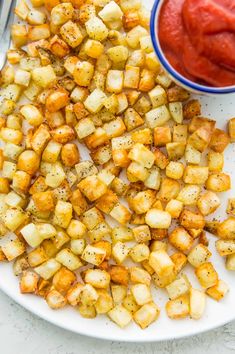 air fryer hash browns on a white plate with ketchup in the background