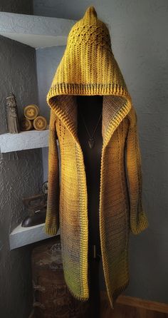 a woman's yellow knitted coat on display in front of a white fireplace