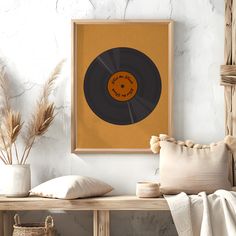 there is a record on the wall next to some pillows and vases with plants