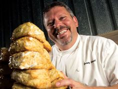 a man sitting in front of a pile of doughnuts on a white plate