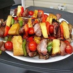 a white plate topped with meat and veggies on top of a wooden skewer