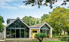 a house that is in the middle of some grass with trees and bushes around it