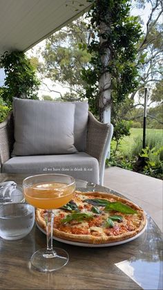 a pizza sitting on top of a wooden table next to a glass of orange juice