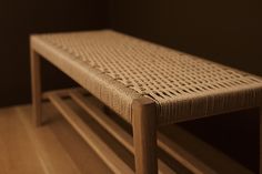 a wooden bench sitting on top of a hard wood floor next to a black wall