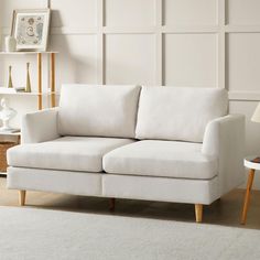 a white couch sitting on top of a rug in a living room next to a lamp