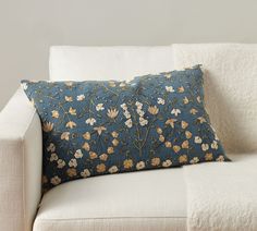 a white couch with a blue floral pillow on it