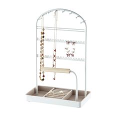 a white jewelry rack with necklaces and earrings hanging from it's sides, on a white background