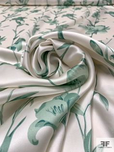 a close up view of the fabric on a bed sheet with green and white flowers