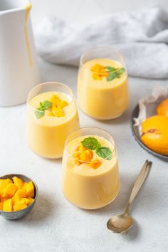 three glasses filled with mango pudding on top of a table