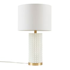 a white lamp with a gold base and a white lampshade on the side